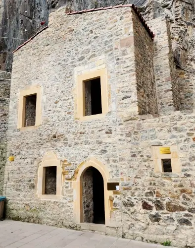 Sümela Manastırı’nın avlusunda yer alan taş mutfak yapısı; sarı taş çerçeveli pencereler, kemerli giriş kapısı ve kayalık yamaca yaslanan özgün mimari detayları.